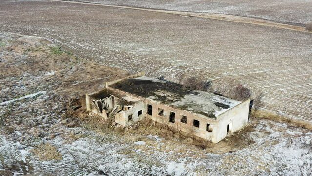 Aerial view of an abandoned industrial building near the agricultural field. Winter time