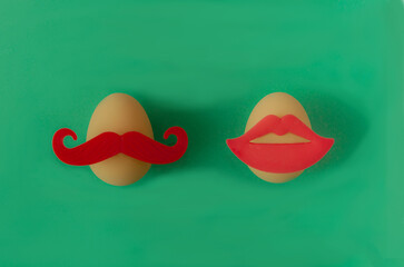 One egg with big red moustaches and one with red lips against green background. Surreal funny creative concept for Easter celebration banner or card. Minimal artistic design for print or advertisement