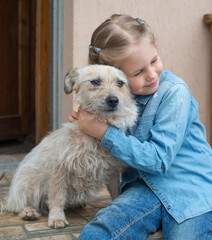 Little girl hugging her dog friend outdoors.