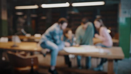 Blurred shot diverse young people interacting on project at library