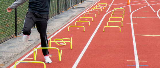 Runner knocking over mini hurdle running on a track