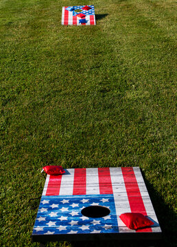 Cornhole boards painted as American flags on a thick green lawn