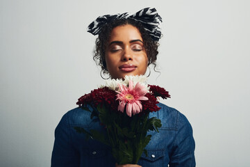 The sweet smell of flowers calms me. Studio shot of an attractive young woman holding a bunch of...