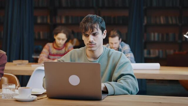 Young man student prepare for examinations at library using laptop