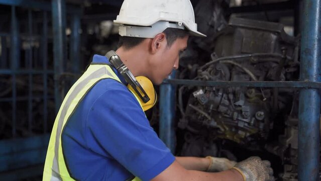 Old car alternators on shelf. Engineer man and Foreman wearing safety helmet standing at recycling yard of old industrial vehicle.