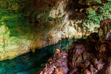 View of beautiful natural pool of crystal clear water formed in a rocky cave with stalagmites and stalagmites. Kuza cave in Zanzibar, Tanzania