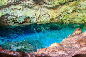 View of beautiful natural pool of crystal clear water formed in a rocky cave with stalagmites and stalagmites. Kuza cave in Zanzibar, Tanzania