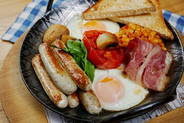 rustic breakfast with sausages, bacon, egg, bread and vegetables