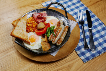 rustic breakfast with sausages, bacon, egg, bread and vegetables