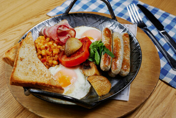 rustic breakfast with sausages, bacon, egg, bread and vegetables