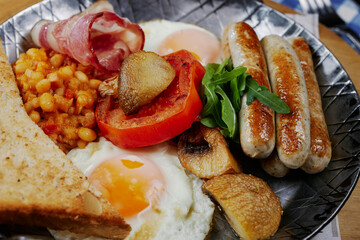 rustic breakfast with sausages, bacon, egg, bread and vegetables