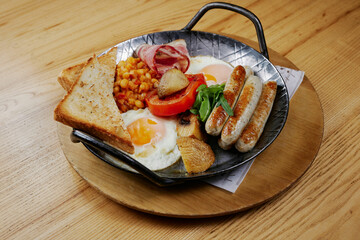 rustic breakfast with sausages, bacon, egg, bread and vegetables