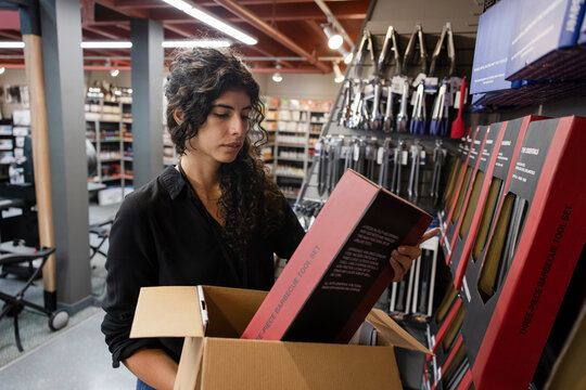 Store worker looking at box of barbeque tool set