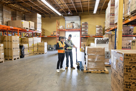 Colleagues planning work with digital tablet in distribution warehouse