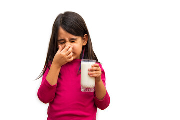 Little girl bothered by the smell of milk is covering her nose on a white background