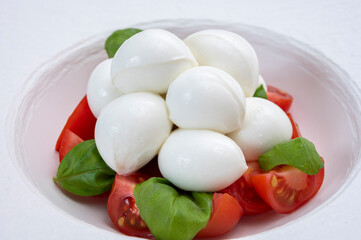 Tasty caprese salad with cherry tomatoes, white mozzarella cheese and green basil leaves