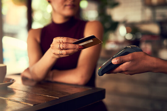Swipe it off my cheque account. Closeup shot of a woman paying using NFC technology in a cafe.
