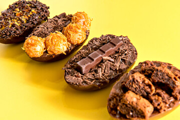 Chocolate filled easter eggs on yellow background.