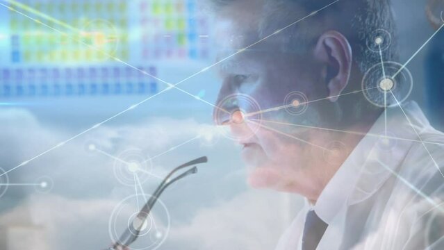 Animation of network of connections over senior caucasian male doctor using laptop