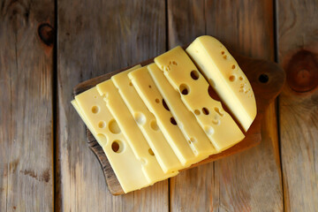 Selective focus. Macro. Cheese with holes slices on a wooden surface.