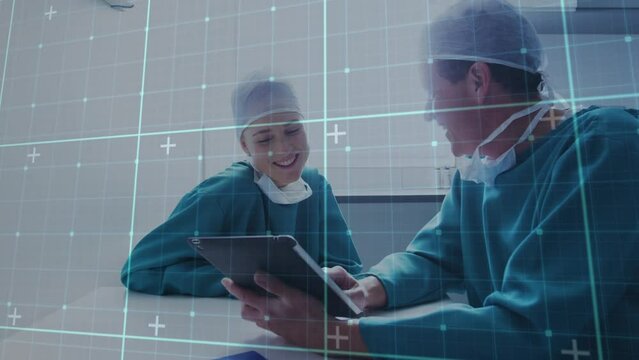Animation of data processing over caucasian male and female surgeons using tablet