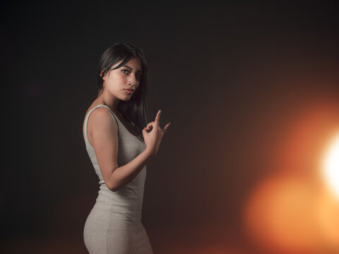 hispanic girl with defiant attitude isolated on black background with fler on one side, alternative rocker model concept.