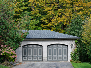 Brick two car garage of home surrounded by trees