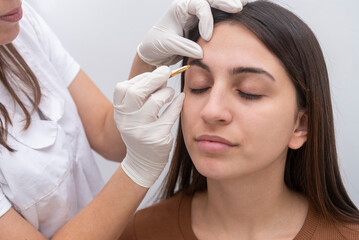 young woman performing a beauty session on the face, eyebrow shaping and eyelash service
