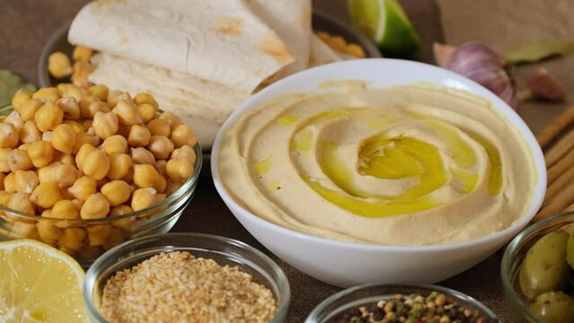 Chickpea hummus made from mashed chickpeas dip with tahini lemon garlic and olive oil close-up. Enjoying yummy hummus with pita, lavash, bread sticks, grissini. Kosher healthy vegan food. Lean dish 