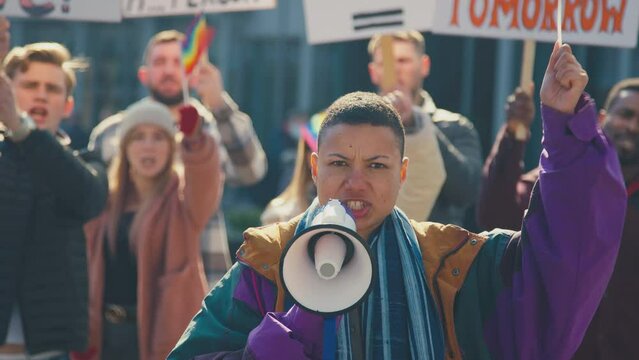 Group of protestors with megaphone holding placards and waving flags on demonstration march to promote gender equality- shot in slow motion