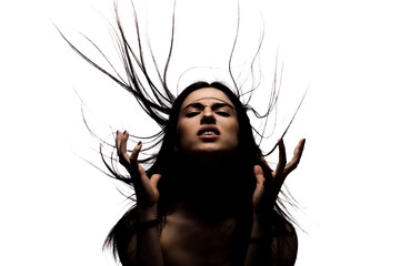 Dark portrait with shadows of an angry girl with hair in the air looking up and making gestures with her hands.