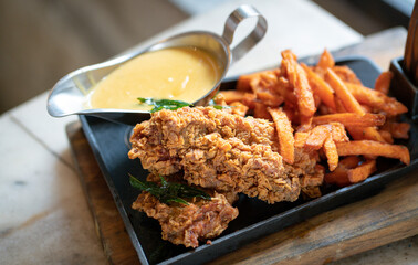 Chicken chop with chips and salted egg sauce on a grill pan.