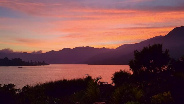 Lake Atitlán Santiago Guatemala | A beautiful sunset of Lake Atitlan with a Mayan boat moving slowly in the center of the lake