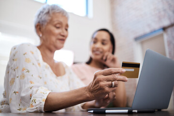 Credit came along to save the day. Shot of a senior woman using a laptop and credit card with her daughter at home.