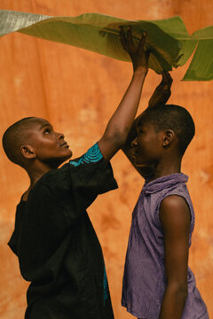 Two young black farmers kids holding a banana leaf