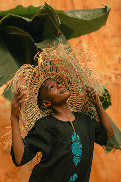Happy portrait of a young black modern farmer wearing a straw hat looking up smiling 