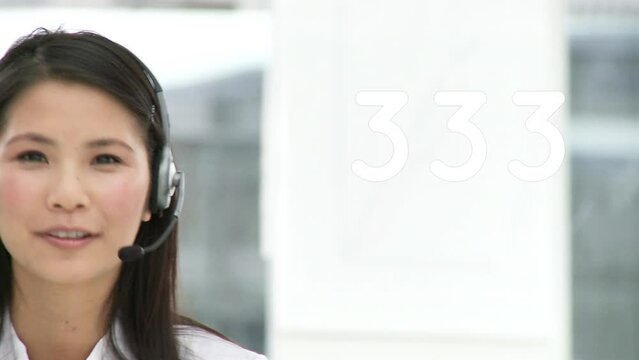 Animation of numbers over asian businesswoman using phone headset