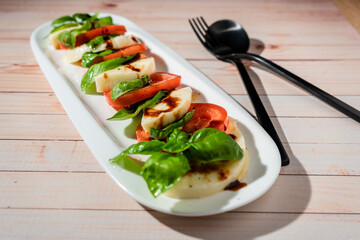 A Classic Italian caprese salad of mozzarella, tomato and basil with olive oil and vinegar.