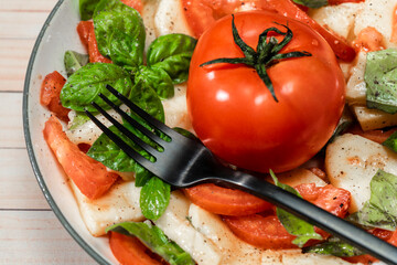 Plate or platter with an Italian caprese salad of mozzarella, tomato and basil with olive oil and vinegar.
