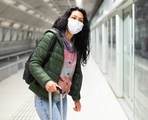 Oriental woman in protective mask going along just arrived train in subway station