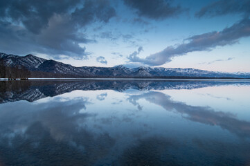 黄昏の湖の水面に映る淡い青の空。