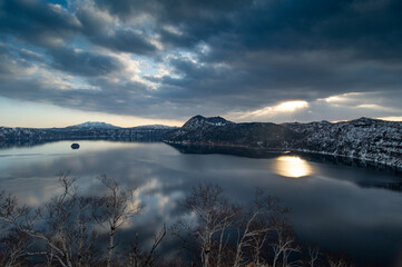 葉の無い木々と曇り空の朝のカルデラ湖。日本の北海道の摩周湖。