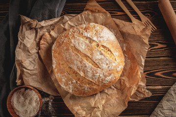 Homemade natural bread with a Golden crust on a napkin on an old wooden background. Baking bakery products. Rustic style