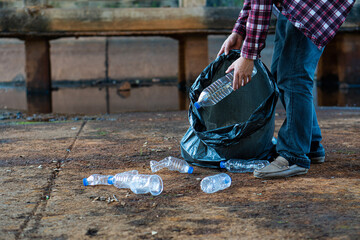The young man's hand held various plastic bottles in a black bag. They are piled together to be...