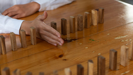 Businessman's hand stops falling wooden blocks and business interruption strategy ideas, solutions Close the hands of a businessman, stop the risk of falling trees on the table.