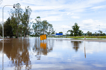 Floodwater rising over water over road sign on highway