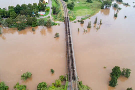 Aerial view of railway track bridge over brown floodwaters