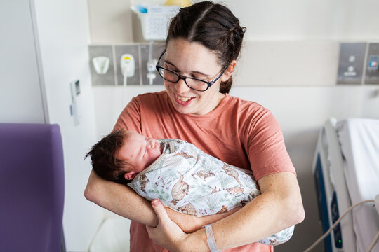 Young parent holding newborn baby in hospital maternity ward after delivery
