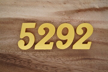 Golden Arabic numerals on a real brown and white wooden floor number 5292