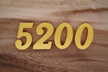 Golden Arabic numerals on a real brown and white wooden floor number 5200